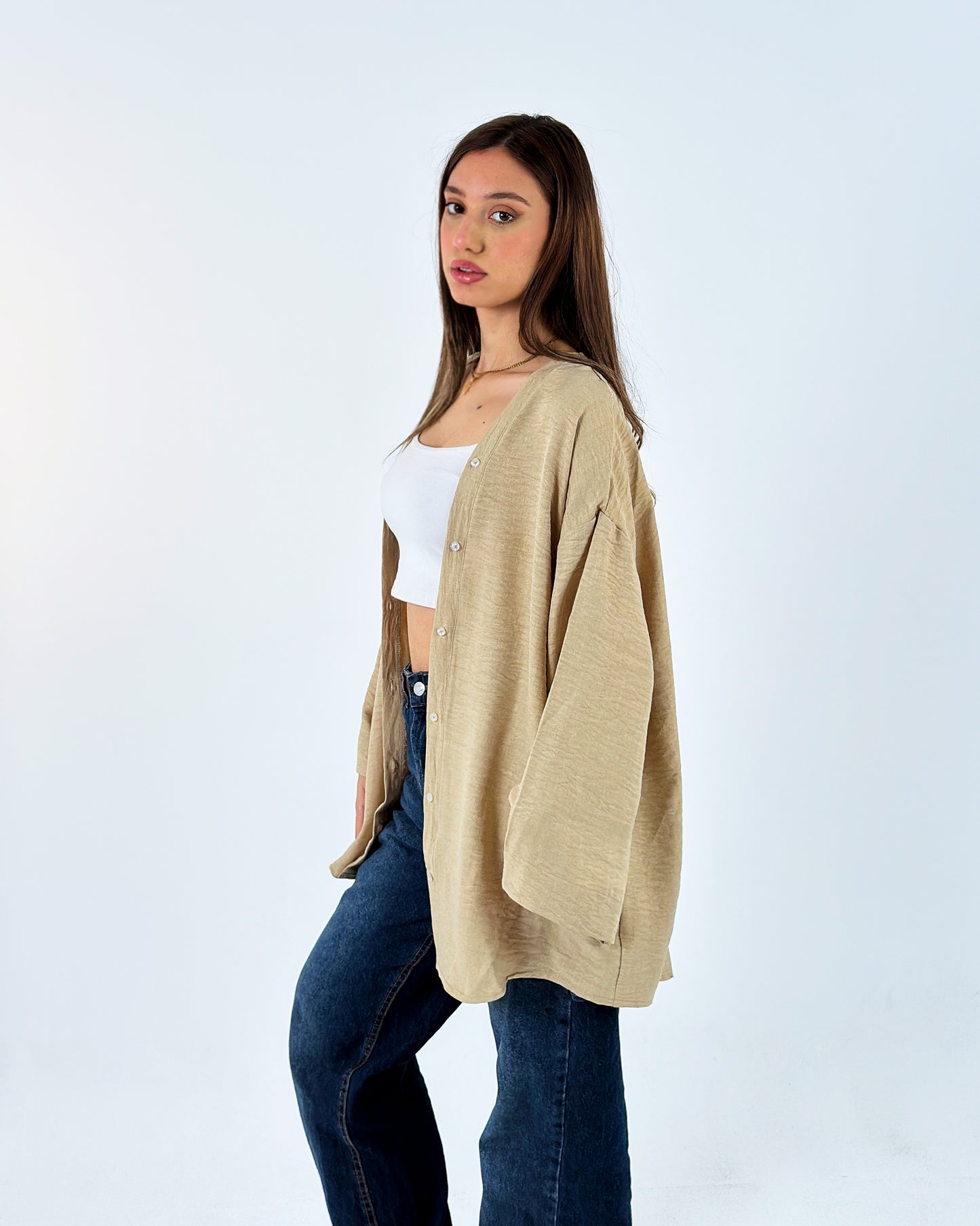 Woman wearing a beige cardigan over a white top and blue jeans